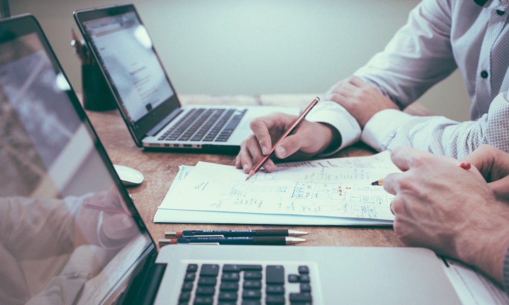 image of people sitting at desk with laptops and note pads